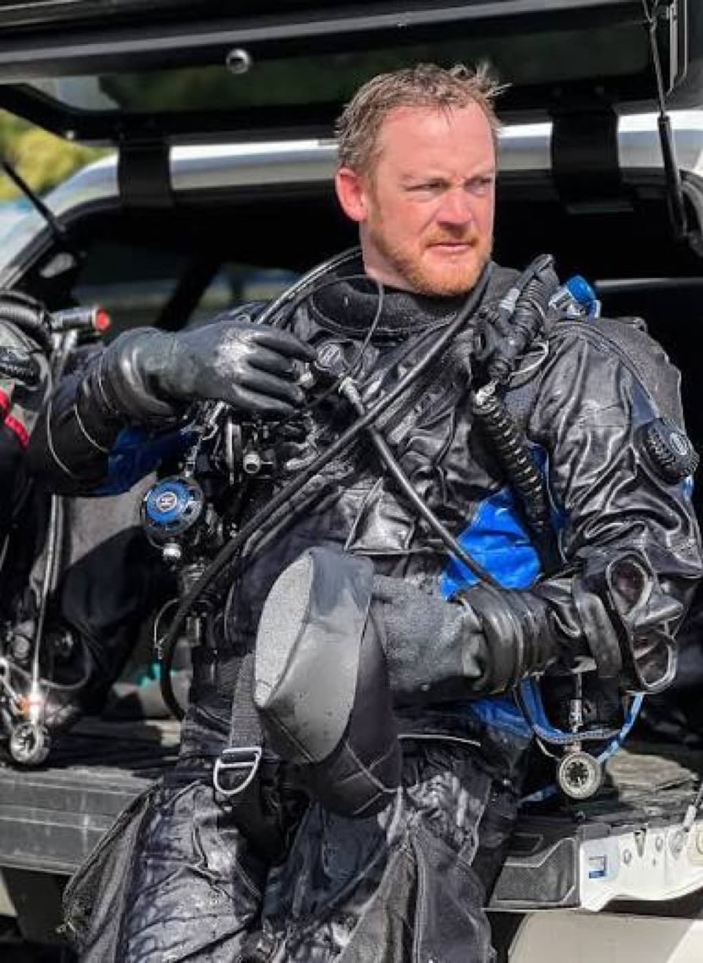 Technical diver in wet gear preparing for a recovery deployment.